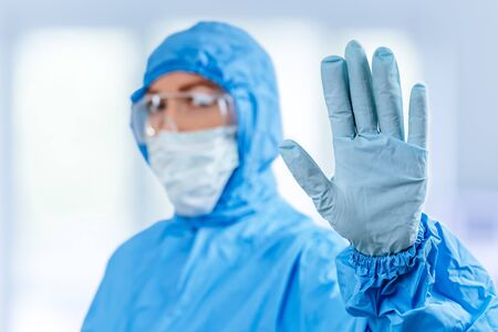 Concept of coronavirus quarantine. Concept of a global coronavirus epidemic. Treatment of coronavirus infection. Medic in hazmat protective suit show hands gesture for stop corona virus outbreakの写真素材