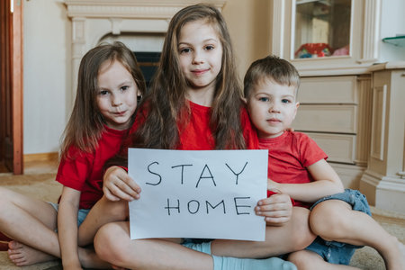 Family stay at home concept. Three children holding sign saying stay at home for virus protection. Quarantine concept.の写真素材