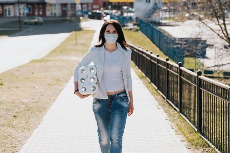 Woman walking in medical mask with toilet paper during coronavirus outbreak or covid-19. concept of covid-2019 quarantine. dangerous COVID virus, people panicの写真素材