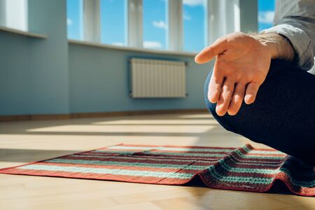 Man practice yoga. Young attractive male doing breathing exercises. Guy meditating at home along...