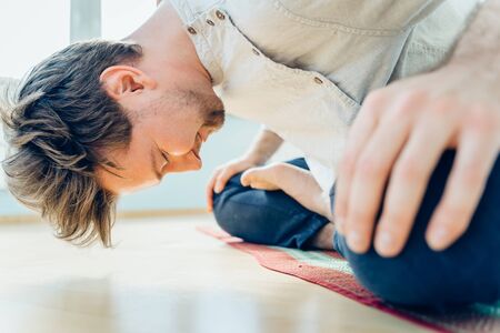 Man practice yoga. Young attractive male doing breathing exercises. Guy meditating at home along during the pandemic. Relaxation and resting concept for isolation. Slide shot.の写真素材
