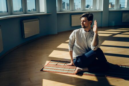 Man practice yoga. Young attractive male doing breathing exercises. Guy meditating at home along during the pandemic. Relaxation and resting concept for isolation. Slide shot.の写真素材