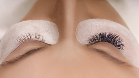 Eyelash Extension Procedure. Close up view of beautiful female eye with long eyelashes, smooth healthy skin.の写真素材