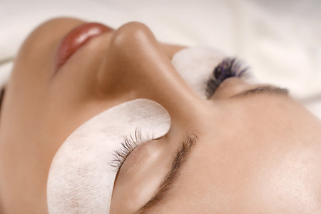 Eyelash Extension Procedure. Close up view of beautiful female eye with long eyelashes, smooth healthy skin.の写真素材
