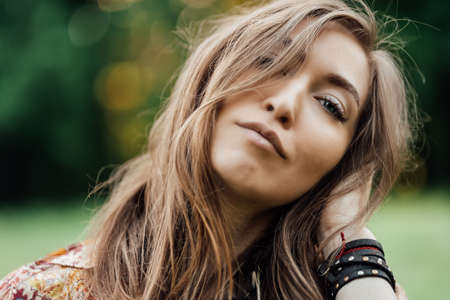 Close up Beautiful young woman wearing bohostyle clothes posing in the rays of the evening sun, sunset. Boho style fashion, female wearing silver jewelry having fun in park outdoors.の写真素材