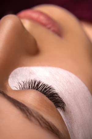Eyelash Extension Procedure. Close up view of beautiful female eye with long eyelashes, smooth healthy skin.の写真素材