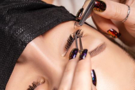 Eyelash Extension Procedure. Beautiful Woman with Extreme Long False Eyelashes. Makeup, Cosmetics. Beauty, Skincare. Woman in medical mask.の写真素材