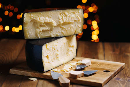 Medium hard cheese head parmesan on wooden board, with cheese parmesan knifes.の写真素材