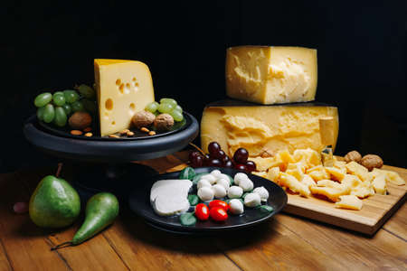 Composition different types of cheese with walnuts and grapes on rustic wooden background.