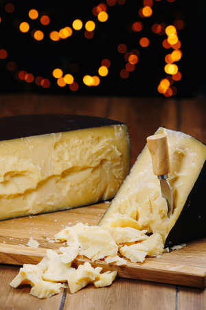Medium hard cheese head parmesan on wooden board, with cheese parmesan knifes.の写真素材