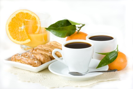 Cups of black coffee, eclairs, juice and fruit.の写真素材