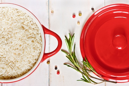 Rice on a red ceramic saucepan and a cover.の写真素材