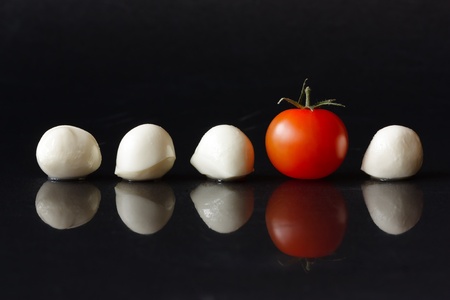 Cherry tomato and small balls mozzarella on a black shiny background.の写真素材