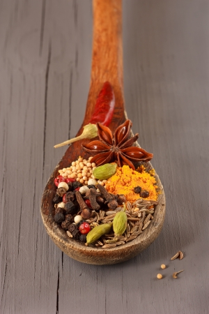 Colorful spices on an old wooden spoon.の写真素材