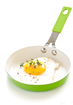 Fried egg with spices and thyme on a green pan for breakfast の写真素材