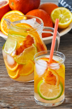 Jug oh fresh cold citrus lenonade with ice cubes on a wooden background.の写真素材