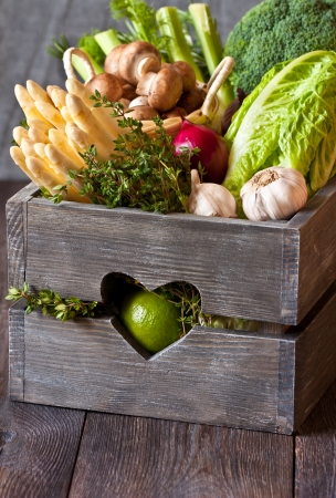 Fresh vegetables and herbs in an old wooden box.の写真素材