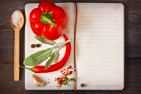 Open recipe book with vegetables  and herbs on a wooden background.の写真素材