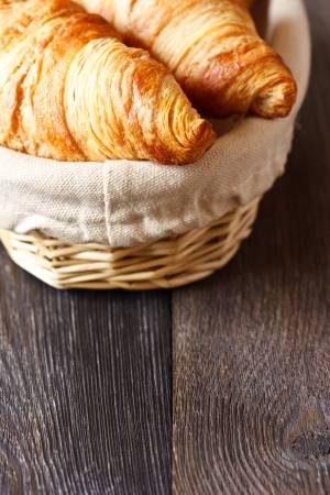 Fresh croissants in a basket on a wooden background with copy space.の写真素材