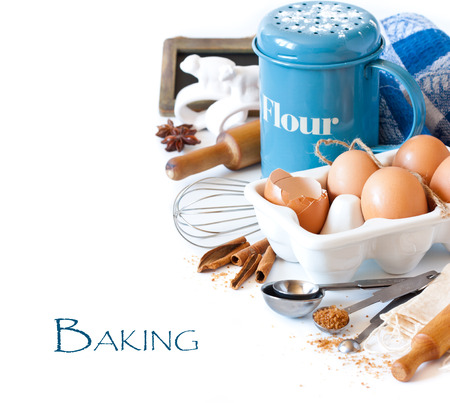 Flour strainer, wooden rolling pin, whisk, measuring spoons and food ingredients for baking on a white.の写真素材