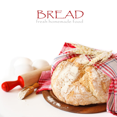 Fresh homemade bread with food ingredients and rustic wooden rolling pin on a white background with copy space for text.の写真素材