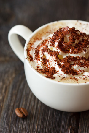 Cup of cappuccino coffee with whipped cream and chocolate close-up.の写真素材