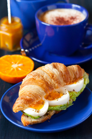 Croissant sandwich with egg and cup of coffee for breakfast.の写真素材