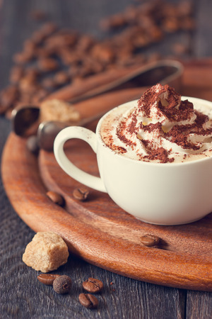Cup of cappuccino coffee with whipped cream and chocolate. Toned photo.の写真素材