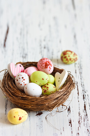 Easter chocolate eggs in a small nest on a white wooden board with copy space for text.の写真素材