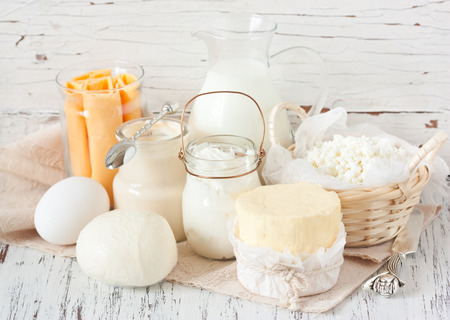 Fresh farm dairy products on a white wooden background. Tasty cheese, butter, eggs, milk and yogurt close-up.の写真素材