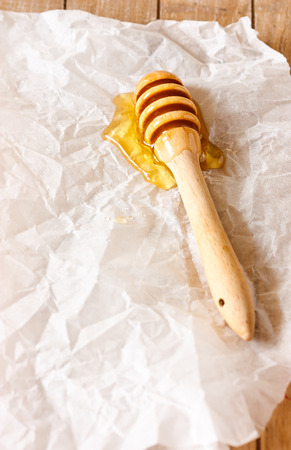 Wooden honey dipper with honey on a crumpled paper with copy space for text.の写真素材