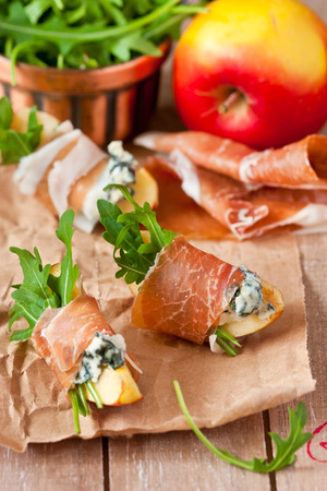 Apple ham cheese appetizer with arugula on a wooden board.の写真素材