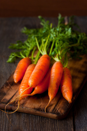 Bunch of fresh carrots  on an old wooden cooking board.の写真素材