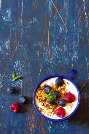 Yogurt with granola and fresh berries on an old wooden board.の写真素材