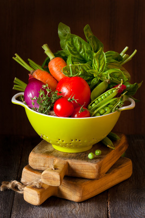 Fresh ripe vegetables with water drops in a green colander.の写真素材