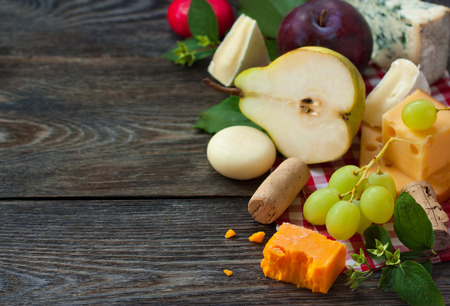 Delicious cheese and fruits on a wooden board. Food ingredients background. Selective focus.の写真素材