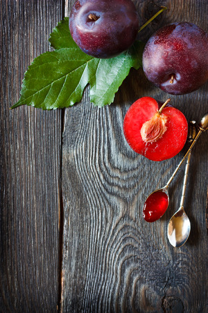 Fresh ripe plums and delicious homemade jam on an old wooden board with place for recipe text.の写真素材