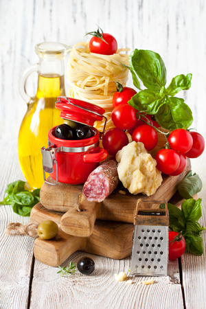 Traditional Italian food. Tagliatelle and salami with fresh tomatoes, cheese, olives and herbs.の写真素材