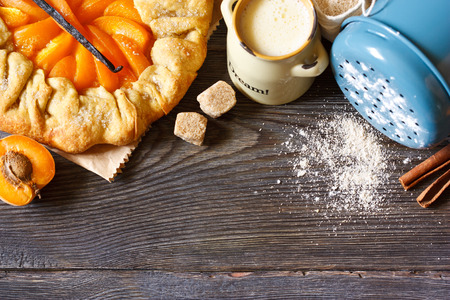 Homemade apricot pie with vanilla and brown sugar on a wooden background with food ingredients for baking.の写真素材