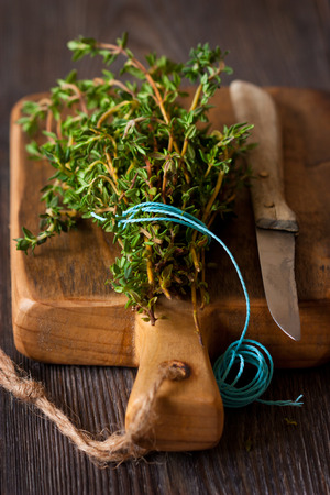 Bunch of fresh thyme and old knife on a cutting board.の写真素材
