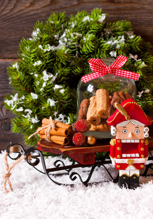 Christmas decoration with decorative nutcracker and sweet cookie in glass bell jar on a sled.の写真素材