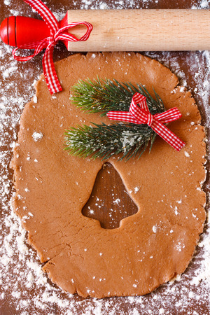 Preparation for baking Christmas cookies. Gingerbread dough with bell cutter cookie and rolling pin.の写真素材