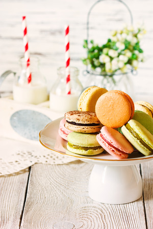Sweer macarons cookies on a cake stand and milk school bottles with straw.の写真素材