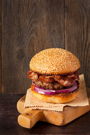 Brutal smoked bacon hamburger on wooden cutting board.の写真素材
