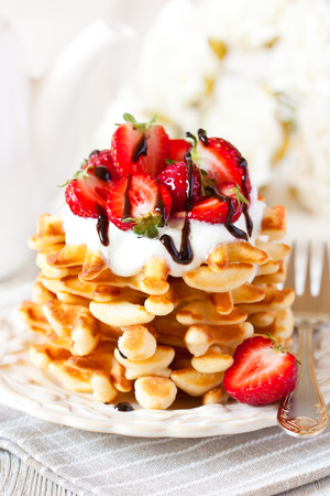 Fresh homemade waffles with whipped cream and strawberryserved chocolate sauce closeup.の写真素材