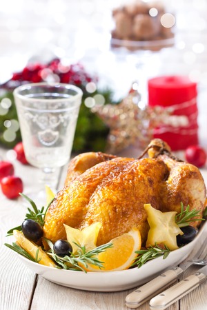 Whole roasted orange chicken with fruit garnish and rosemary for Christmas dinner.の写真素材