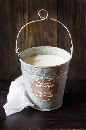 Bucket of fresh farm milk on old wooden board.の写真素材