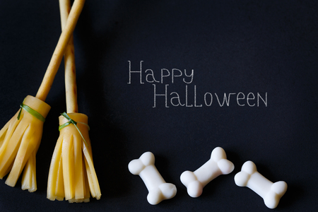 Halloween pretzel stick cheese broom and sugar bones on black.の写真素材