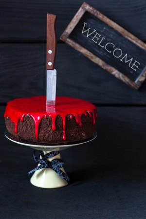 Bleeding monster cake with knife on cakestand and welcome tag.の写真素材