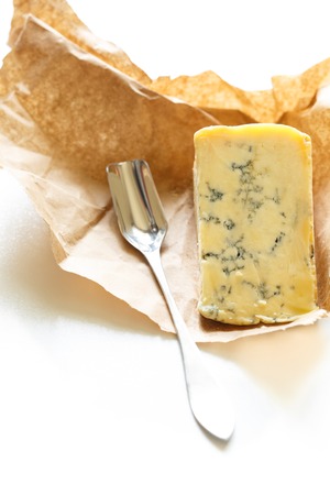 Slice of blue Stilton cheese and stilton spoon on a white backgroundの写真素材
